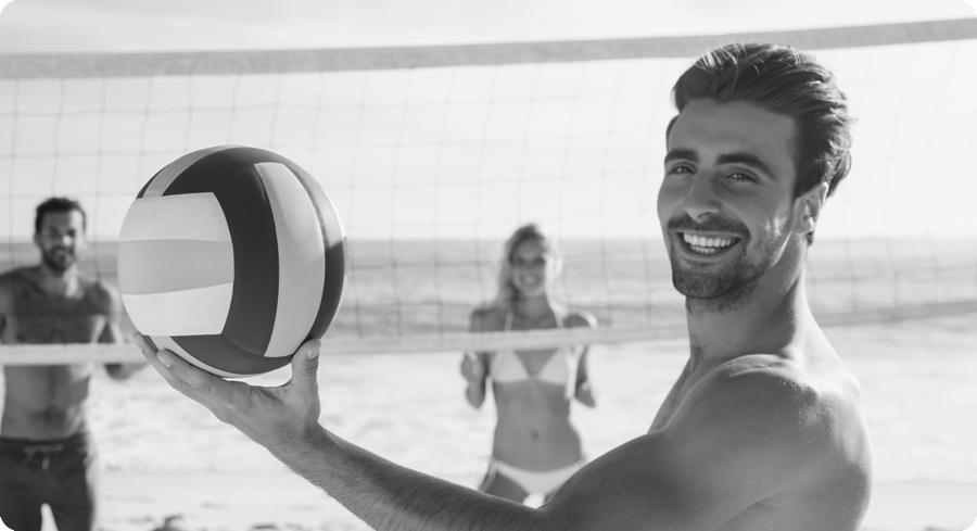 Hombre jugando a voley en la playa con amigos